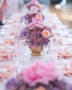 the table is set with pink and purple flowers