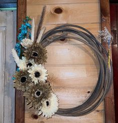 flowers are arranged on the side of a wooden door with a cowboy lasso as decoration