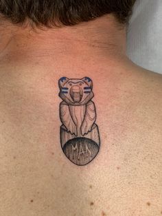 a tattoo on the back of a man's neck that has a koala bear sitting on top of it