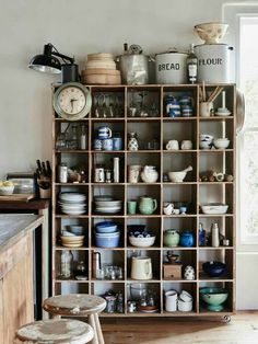 a room filled with lots of different types of dishes on shelves next to a window