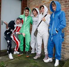 four people in matching onesuits posing for the camera outside an apartment building with brick walls