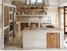 a kitchen with stone walls and flooring next to an open door that leads to another room