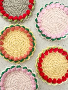 four crocheted coasters sitting on top of a white countertop next to each other