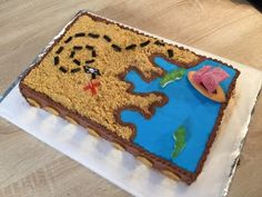 a birthday cake with a pirate map on it's side and decorations around the edges