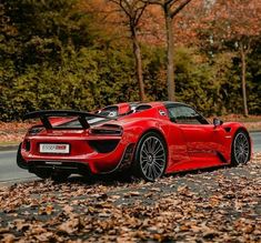 a red sports car is parked on the side of the road in front of some trees