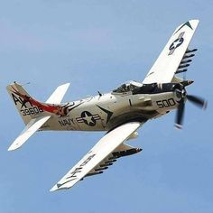 an airplane flying in the air with propellers on it's wings and landing gear down