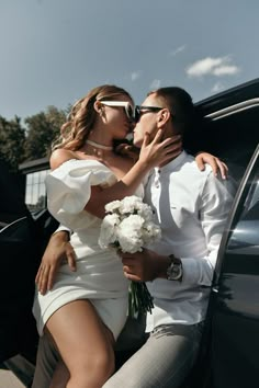 a man and woman kissing in front of a car