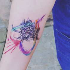 a colorful tattoo on the arm of a woman's left arm, with an abstract design