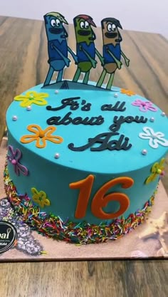 a birthday cake decorated with cartoon characters on top of a wooden table next to a sign that says, it's all about you 16