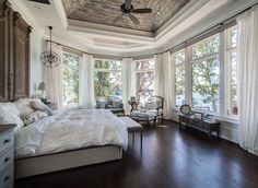 a bedroom with wood floors and large windows