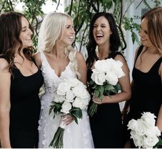 three beautiful women standing next to each other holding bouquets in their hands and laughing