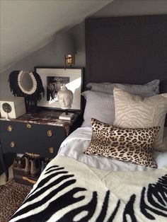 a bedroom with a zebra print blanket on the bed and black dresser next to it