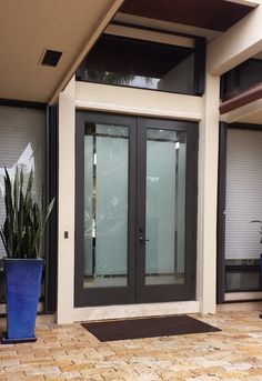 an entrance to a building with two blue planters on the ground and one large door