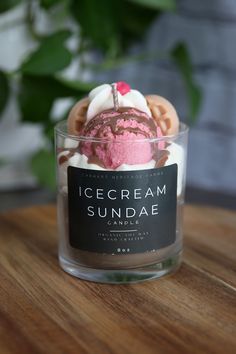 an ice cream sundae sits in a glass container on a wooden table next to a potted plant