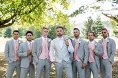 a group of men standing next to each other in front of a lush green tree