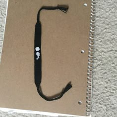 a spiral notebook with a black cord attached to it on top of a carpeted floor