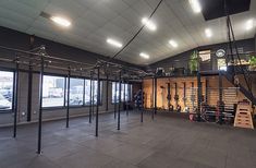 the inside of a gym with several racks and ladders on the wall, in front of large windows