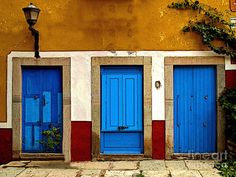 three blue doors in front of a yellow building