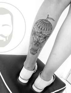 a woman's leg with a tattoo on it and a hot air balloon in the sky