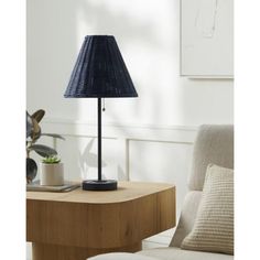 a lamp on a table next to a chair and potted plant in a living room