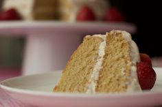 a piece of cake with white frosting and strawberries on the plate next to it