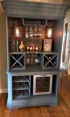 a gray hutch with wine glasses on the top and an open shelf above it