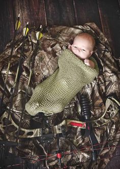 a baby wrapped in a blanket is laying next to some fishing rods and other items