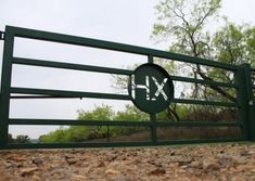 there is a green gate with the letters x and y on it in front of some trees