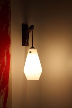 a white light hanging from the side of a wall next to a red and white wall