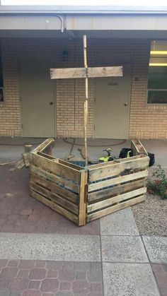 a wooden boat made out of pallets on the side of a building with brick walls