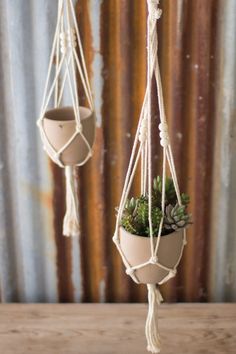 two hanging planters with succulents in them on top of a wooden table