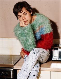 a young man sitting on top of a counter next to a toaster