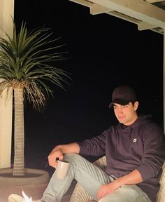 a man sitting on a chair next to a lit candle and a potted plant