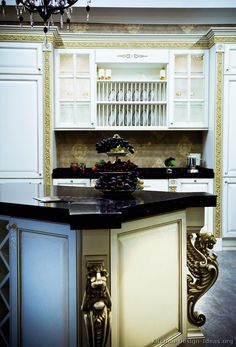 a fancy kitchen with white cabinets and black counter tops, chandelier above the island