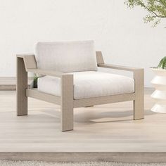 a white chair sitting on top of a wooden floor next to a potted plant