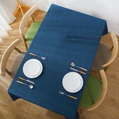 a blue table cloth with two plates and silverware on it, sitting in front of a wooden chair