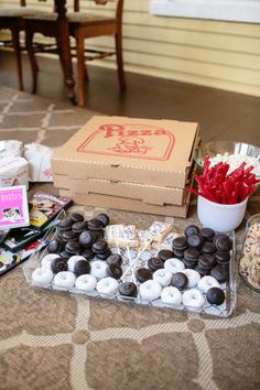 a table topped with lots of chocolate covered donuts next to a box of candy