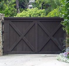 the gate is made of wood and has an iron bar at the top, along with stone pillars on both sides