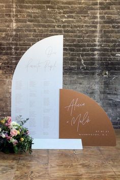 a sign and flowers on the floor next to a brick wall with writing on it