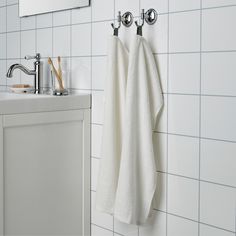 a white towel hanging on the wall next to a sink with two faucets