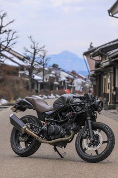 the motorcycle is parked on the side of the road in front of houses and trees