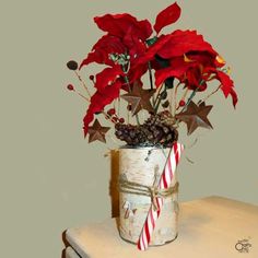 a vase filled with red flowers on top of a wooden table next to a candy cane