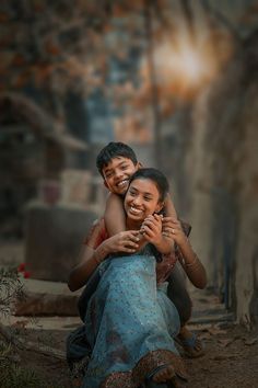 two people sitting on the ground hugging each other