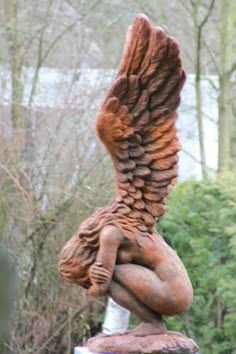 a statue of an angel holding a baby in its arms with trees and bushes behind it