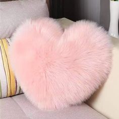 a pink heart shaped pillow sitting on top of a couch