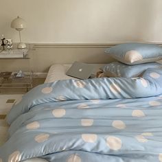 a laptop computer sitting on top of a bed covered in blue and white polka dots