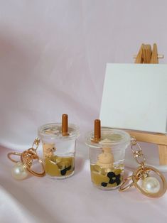 three small glass jars with key chains on them, one filled with liquid and the other empty