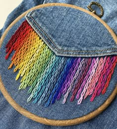 a close up of a piece of cloth with colorful thread on it and a wooden hoop