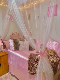 a bedroom with pink and leopard print bedding, white curtains and lights on the ceiling