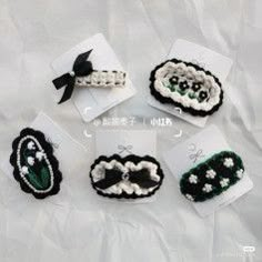 four pieces of crocheted hair accessories are displayed on a white sheet with black ribbon